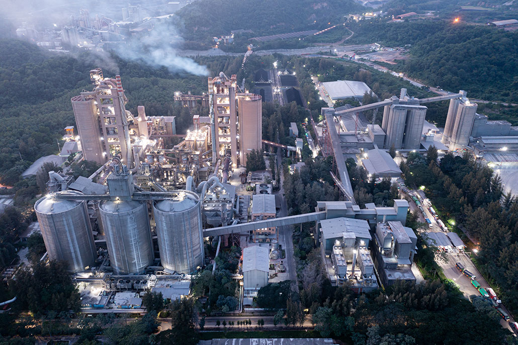 una vista aérea de una fábrica de cemento con humo que se libera activamente de las chimeneas