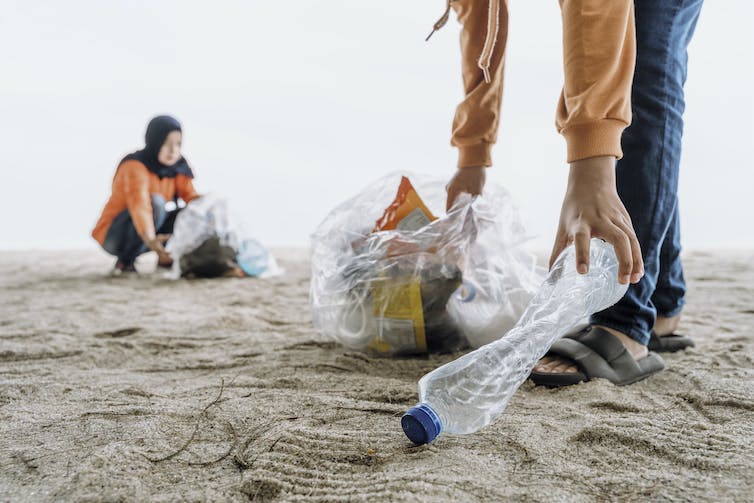 Gente limpiando plástico de una playa