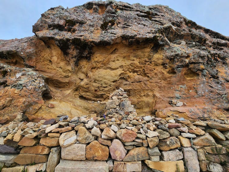 Una pequeña pila de piedras se encuentra frente a una colina de color arena.
