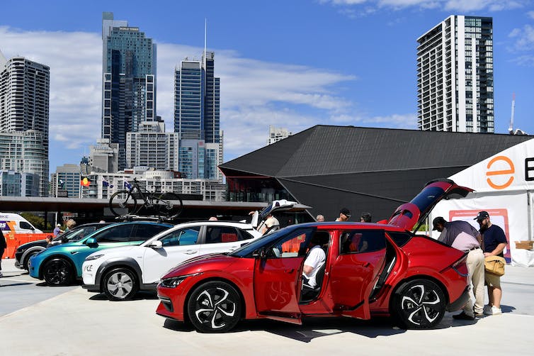 La gente inspecciona los autos alineados en una exposición de vehículos eléctricos