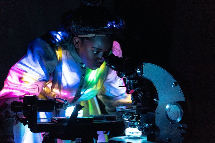 Una mujer vista mirando en un microscopio.