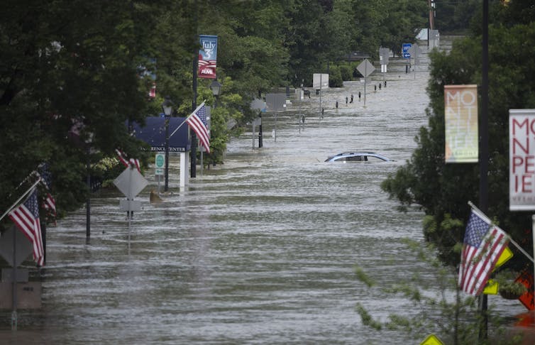calle inundada con banderas estadounidenses y auto sumergido