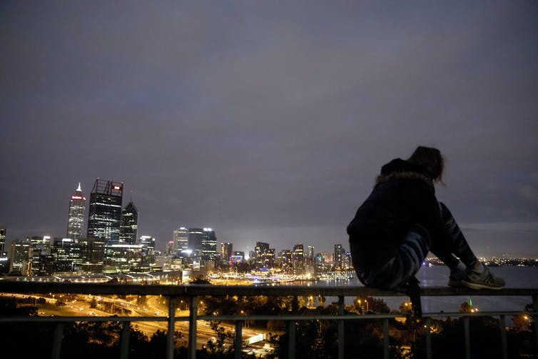 silueta de hombre sentado frente al horizonte de la ciudad