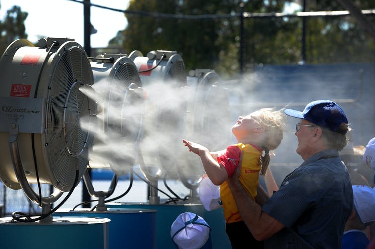 hombre sosteniendo a un niño frente a una máquina de niebla fría
