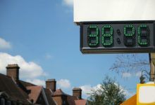 Un termómetro digital frente a una hilera de casas marcaba 38°C.