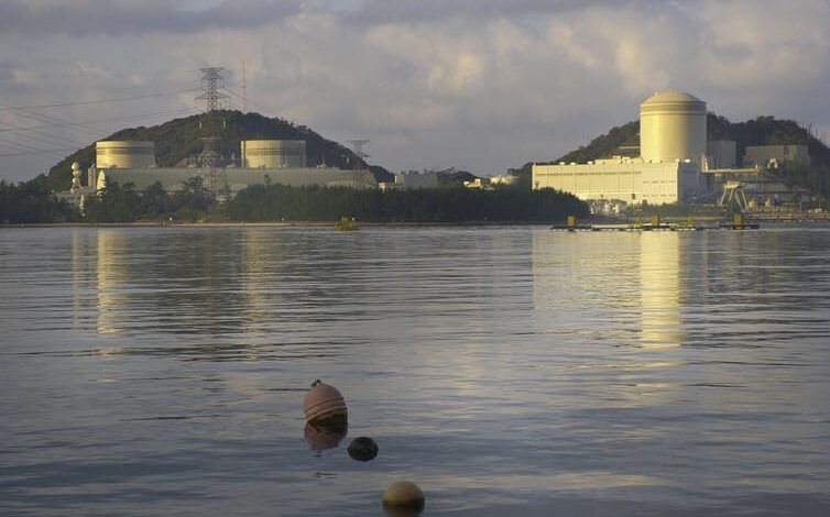 Una gran instalación nuclear en una colina frente a un cuerpo de agua.