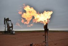 Las bengalas queman gas natural en pozos de petróleo con plataformas de perforación en el fondo.