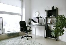 Oficina en casa moderna con escritorio, monitor, silla y estantería.