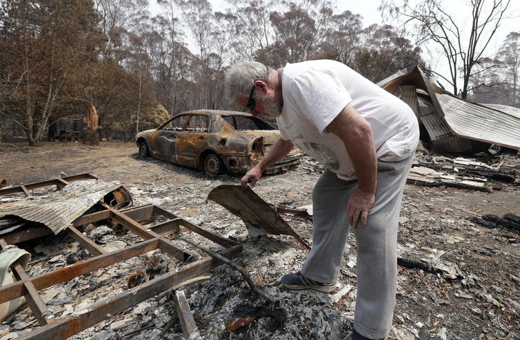 El hombre examina los escombros de su casa quemada