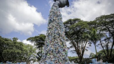 Una escultura de arte gigante muestra un grifo que arroja una botella de plástico.