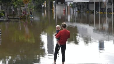 mujer sosteniendo a un bebé con inundación en el fondo