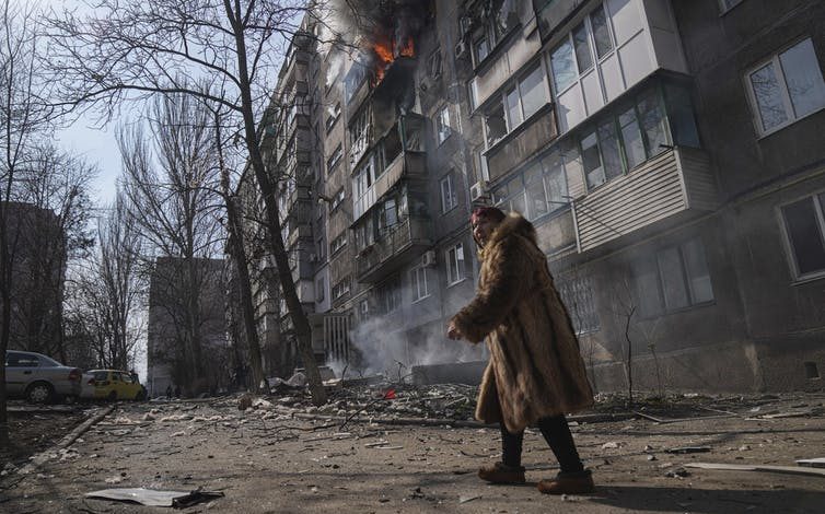 Un hombre pasa frente a un apartamento bombardeado.