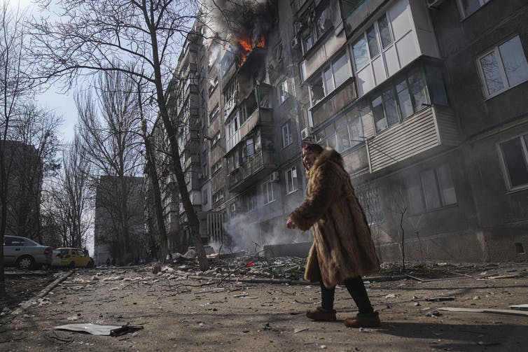 Un hombre pasa frente a un apartamento bombardeado.