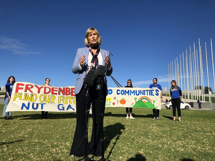 Mujer de pie frente al cartel de protesta climática