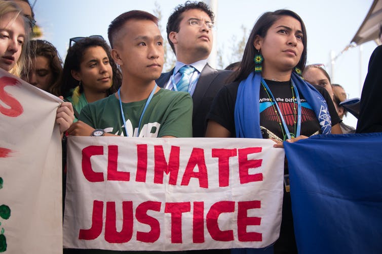 Personas con un cartel que dice 'Justicia climática'