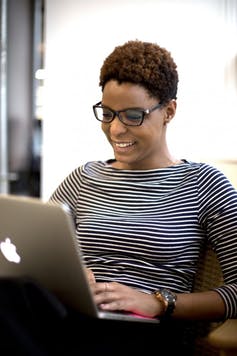 Una mujer se sienta en una videoconferencia con una computadora portátil en las manos.
