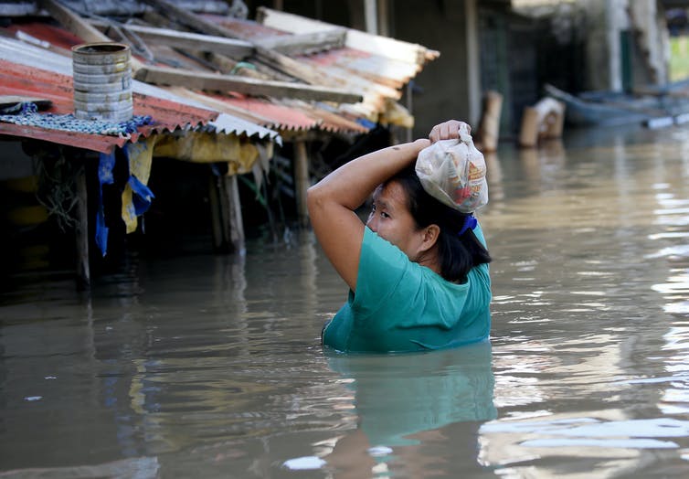Una mujer vadea una calle inundada durante un tifón en Filipinas