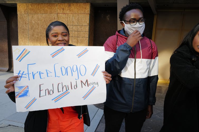 Una persona sostiene un cartel que dice '#FreeCongo End Child Mining'