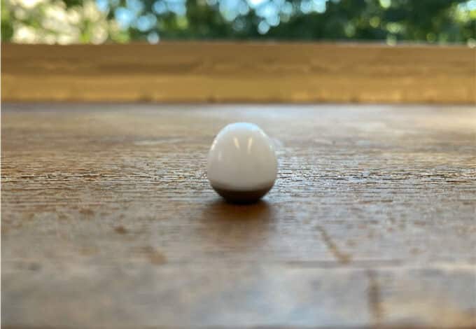 una foto de un objeto parecido a un huevo blanco sobre una mesa de madera