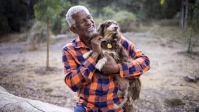 Un anciano negro con un lindo dachshund de pelo largo al aire libre