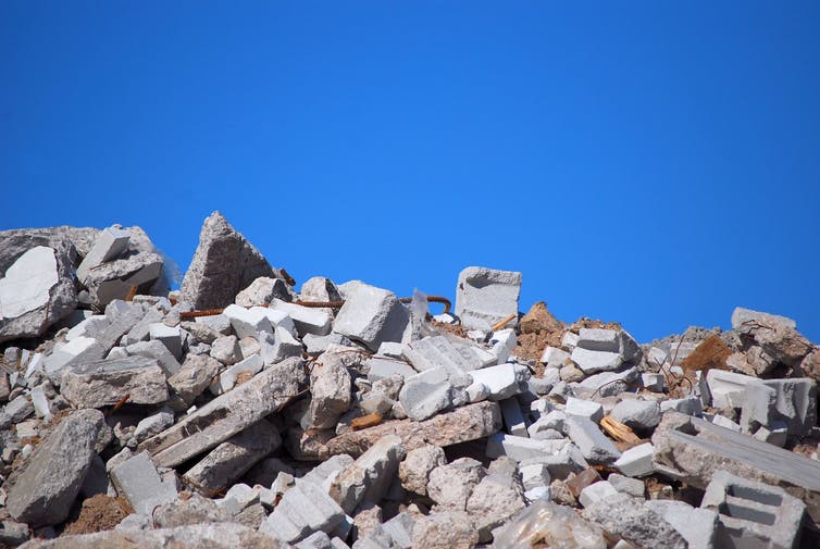 Escombros de hormigón de un edificio demolido contra un cielo azul.