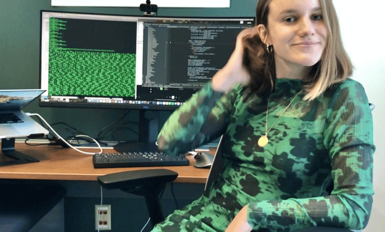una mujer con un vestido negro y verde se sienta en un escritorio con una computadora
