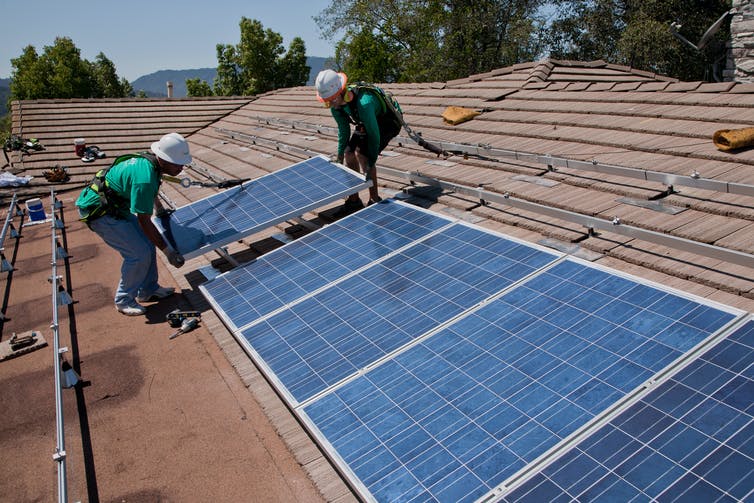 Dos hombres instalando paneles solares en una azotea
