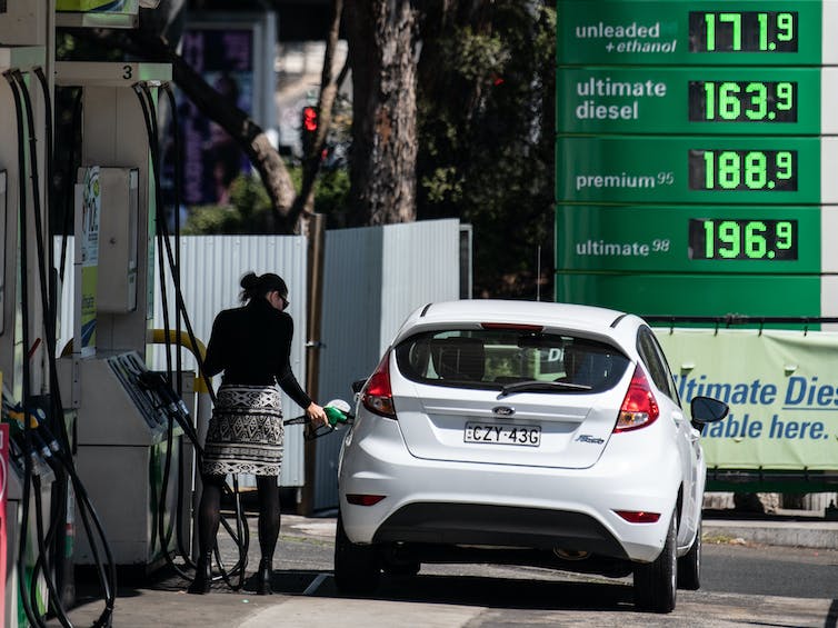 mujer llena auto blanco con gasolina