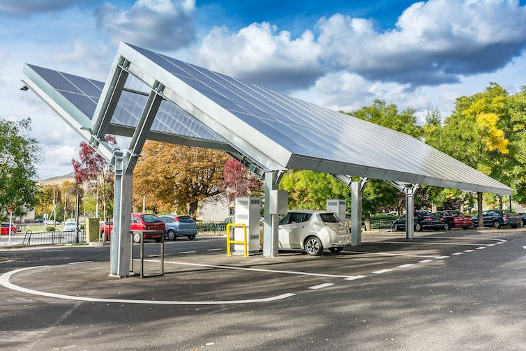 Dos conjuntos de paneles solares suspendidos en ángulo sobre un automóvil estacionado.
