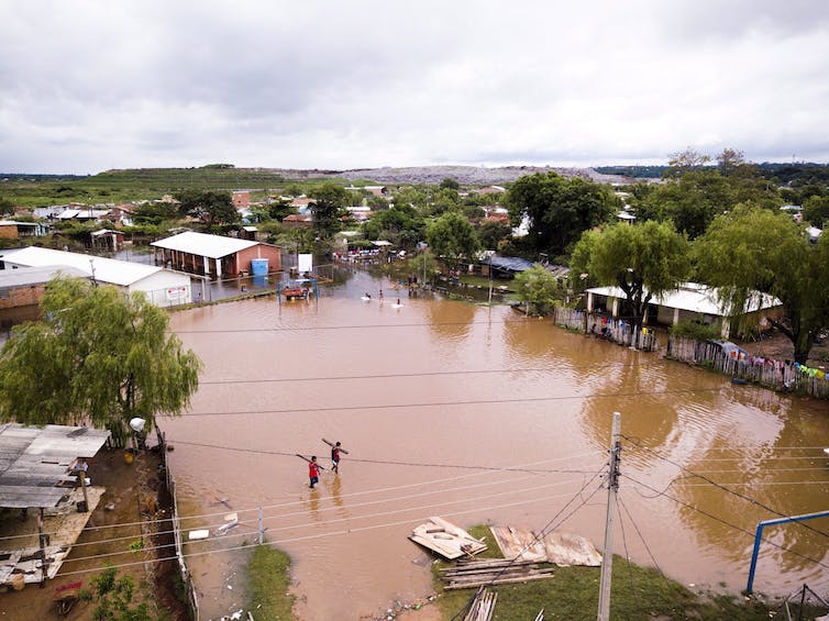 Hombres con tablas caminan por un campo de fútbol inundado