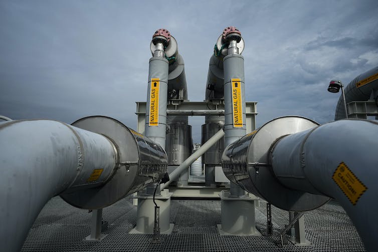 dos grandes tuberías industriales conducen a una plataforma receptora contra un cielo gris