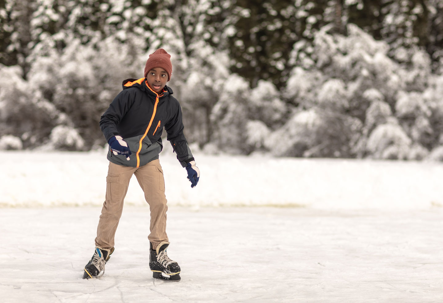 Un niño con ropa de invierno patina sobre la superficie congelada de un estanque