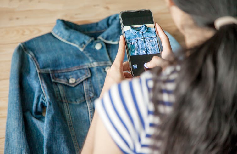 Mujer usando el teléfono para tomar una foto de una camisa.