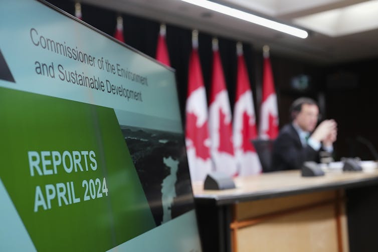 Un hombre se sienta en una mesa frente a banderas.